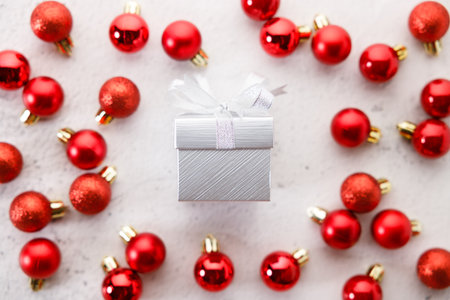 white gift box tied with bows on white marble background. Christmas decorations and red balls on...