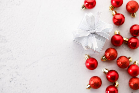 white gift box tied with bows on white marble background. Christmas decorations and red balls on white background. Christmas New year concept. Top view.の写真素材