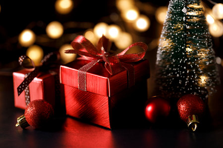 Miniature snowy Christmas tree with red present boxes decorated in bow on black background. Christmas and New year concept.の写真素材