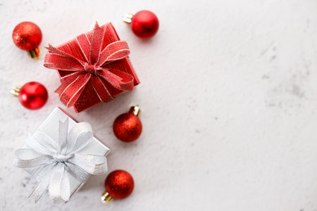 Red and white gift boxes tied with bows on white marble background. Christmas decorations and red balls on white background. Christmas New year concept. Top view.の写真素材