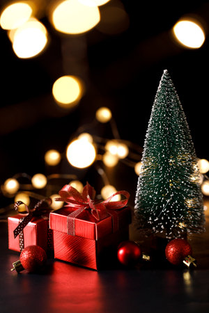 Miniature snowy Christmas tree with red present boxes decorated in bow on black background. Christmas and New year concept.の写真素材