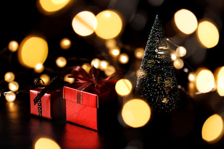 Miniature snowy Christmas tree with red present boxes decorated in bow on black background. Christmas and New year concept.の写真素材