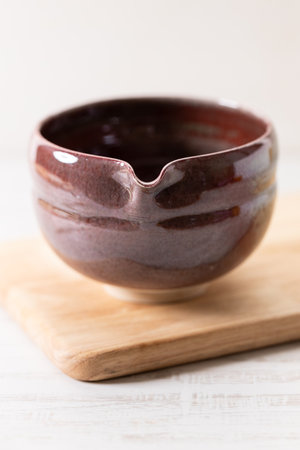 Red spouted tea bowl, Katakuchi, on white wooden background. Closeup.の写真素材