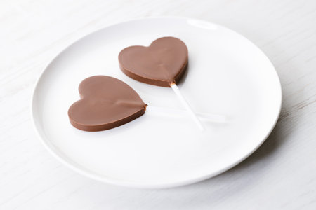 Delicious dark chocolate in heart shaped on white wooden background.の写真素材