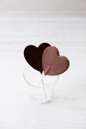 Delicious dark chocolate in heart shaped on white wooden background.の写真素材