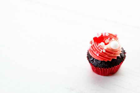 Chocolate cupcake with pink color buttercream in red present box on white wooden background. Sweet and love concept.の写真素材
