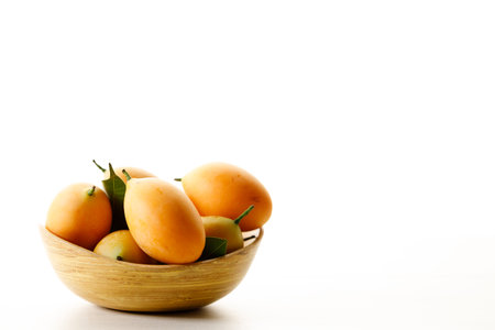Ripe plum mangoes, fresh and juicy fruit with yellow peel, in wooden tray. Selective focus. Tropical...