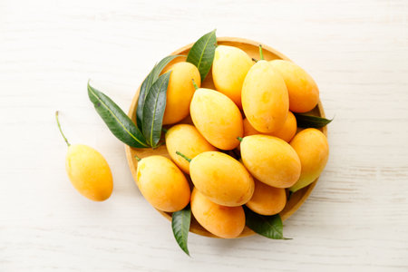 Ripe plum mangoes, fresh and juicy fruit with yellow peel, in wooden tray. Selective focus. Tropical...