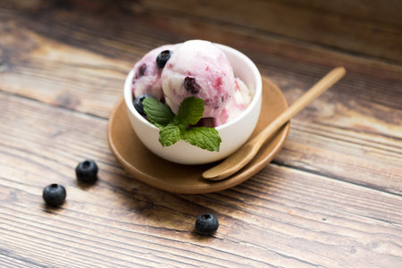 Blueberry yogurt ice cream with fresh blueberries and mint leaves in white cup. Closeup.の写真素材