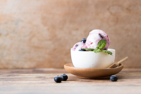 Blueberry yogurt ice cream with fresh blueberries and mint leaves in white cup. Closeup.の写真素材