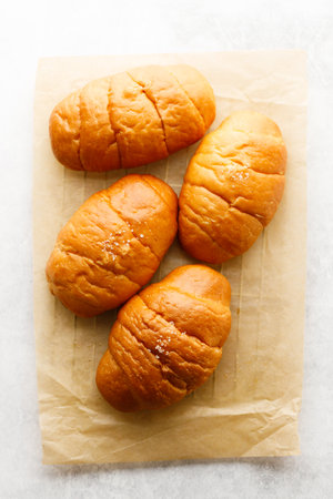 Close up plate of Shio Pan, Japanese salted butter rolls on brown baking paper.の写真素材