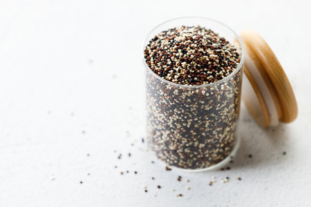 Colorful dried quinoa seeds. Mix of white, black and red quinoa seeds in glass jar. Closeup.の写真素材