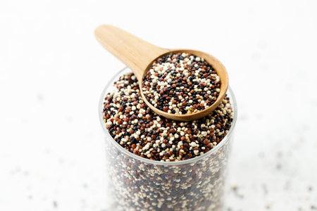 Colorful dried quinoa seeds. Mix of white, black and red quinoa seeds in wooden spoon. Closeup.の写真素材