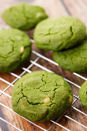 Green tea matcha cookies with white chocolate chips on cooling rack on wooden table. Freshly baked pastries with green tea. Closeup.の写真素材