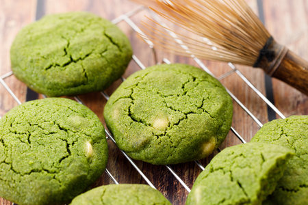 Green tea matcha cookies with white chocolate chips on cooling rack on wooden table. Freshly baked pastries with green tea. Closeup.の写真素材