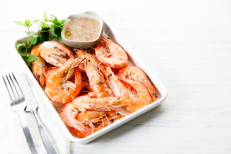 Grilled shrimps with spicy sauce in a white tray on white wooden table. Healthy food. Summer food.の写真素材