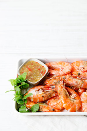Grilled shrimps with spicy sauce in a white tray on white wooden table. Healthy food. Summer food.の写真素材