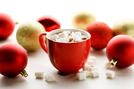 Hot chocolate in red cup with white small marshmallows on white wooden table background.の写真素材
