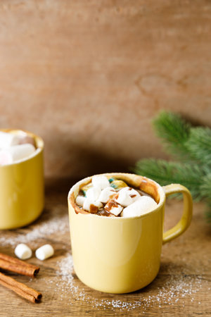 Hot chocolate in yellow cup with white small marshmallows on wooden table background.の写真素材