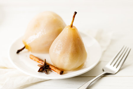 Delicious poached pears on white plate with cinnamon stick and star anise. Delicious and easy dessert.の写真素材