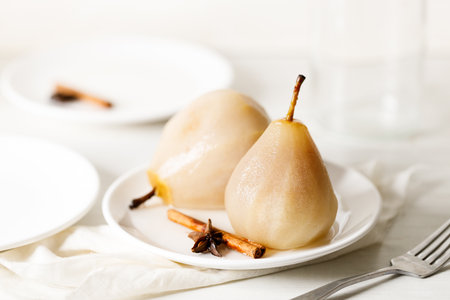 Poached pears on white plate with cinnamon stick and star anise. Easy dessert.の写真素材