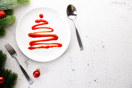 White plate with tomato sauce in Christmas tree shape on white wooden background. Christmas party concept.の写真素材