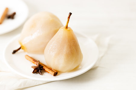Delicious poached pears on white plate with cinnamon stick and star anise. Delicious and easy dessert.の写真素材