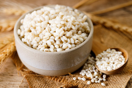 Close up of cooked barley grains and beardless wheat ears on wooden table.の写真素材