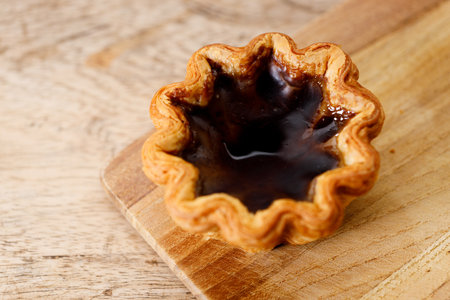 Closeup of coffee Portuguese sweet dessert egg tart on wooden table.  Selective focus. Top view.の写真素材