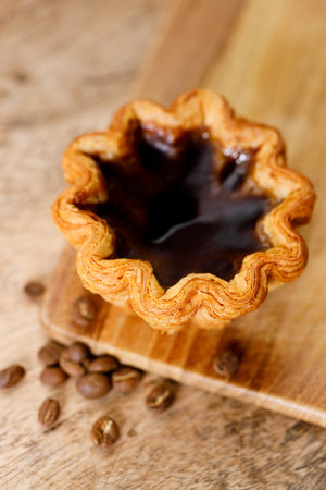 Closeup of coffee Portuguese sweet dessert egg tart on wooden table.  Selective focus. Top view.の写真素材