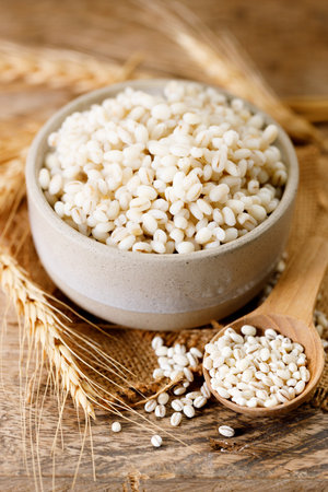 Close up of cooked barley grains and beardless wheat ears on wooden table.の写真素材