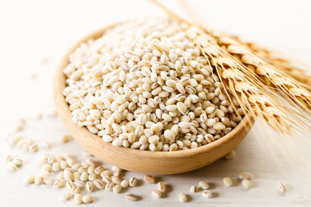Barley grains in wooden cup on white wooden table. Closeup of barley healthy food.の写真素材