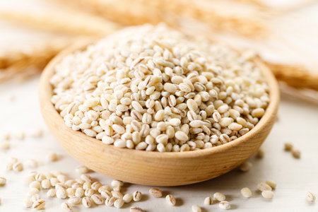 Barley grains in wooden cup on white wooden table. Closeup of barley healthy food.の写真素材