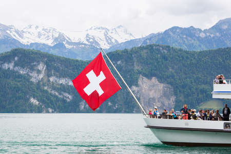 Lucerne, Switzerland June 9 2013: Ferry boat with flag flying carrying passengers on Lake Lucerne