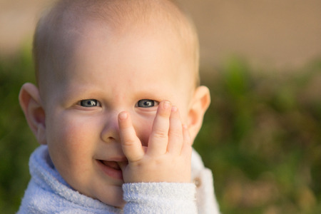 Cute happy baby boy outdoors with thumb in mouthの写真素材