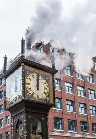 The historic steam clock strikes midday in Gastown, downtown Vancouver, with jets of steam rising from the clockの写真素材
