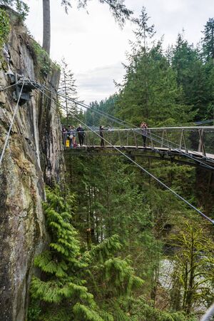 Vancouver, Canada - January 28, 2017: A suspension bridge hanging from a cliff face high above the canyon at the Capilano Suspension Bridge Parkのeditorial素材