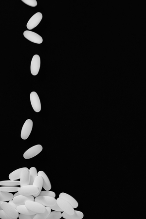Many pills falling into a pile on black backgroundの写真素材