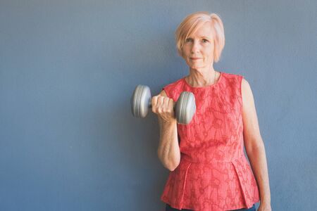 Mature woman keeping fit by lifting weights at home