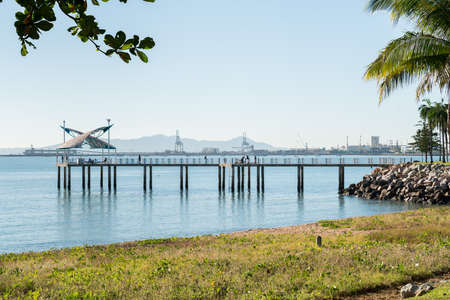 Fishermen in the morning on a warm winter's day on the Strand jetty, Townsville with the port behindの写真素材
