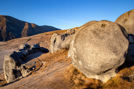 A huge round boulder sits among the castle like rocks on the hillside in the valley at Castle Hill, New Zealandの写真素材