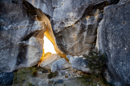 A gap in a limestone rock wall allows the early morning light to filter throughの写真素材