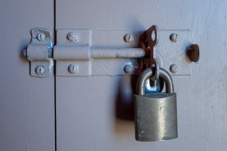 Locked steel padlock on an old grey painted doorの写真素材