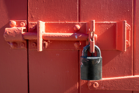 A red painted door with a locked padlock