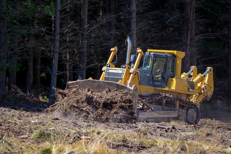Windwhistle, Canterbury, New Zealand - February 9 2019: A large yellow bulldozer pushes stumps and...