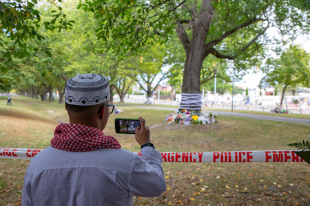 Christchurch, Canterbury, New Zealand, March 22 2019: A Muslim man takes photos of the floral...