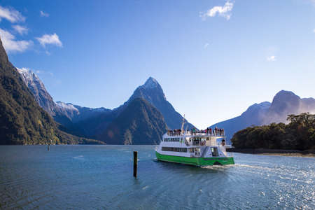 Milford Sound, Fiordland, New Zealand, June 20 2020:Tourists on board a cruise boat heading out into Milford Sound with Mitre Peak in the distanceのeditorial素材