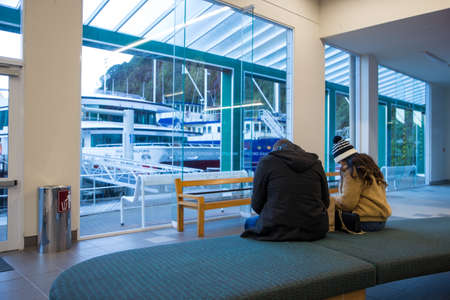 Milford Sound, Fiordland, New Zealand, June 19 2020: Two New Zealand tourists in the ferry terminal at Milford Sound, waiting to go on a cruiseのeditorial素材