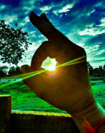 Beautiful sunset between fingers.sun between finger on field.