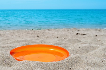 orange frisbee sport disk in sand on beachの写真素材